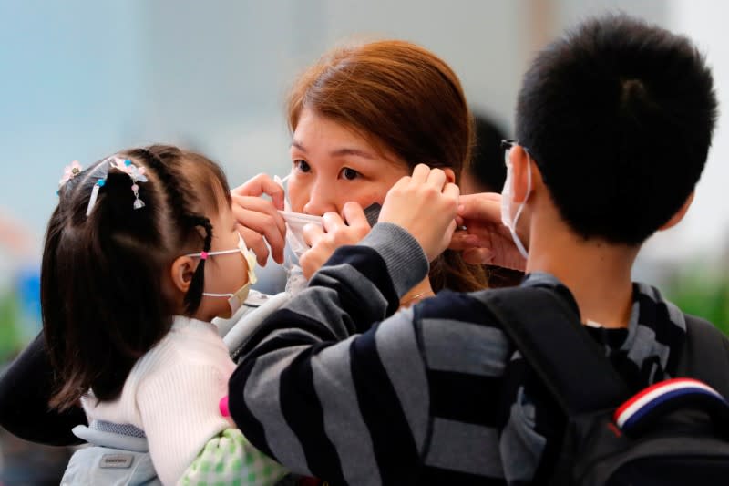 A woman adjusts her mask to prevent an outbreak of a new coronavirus at the Hong Kong West Kowloon High Speed Train Station, in Hong Kong