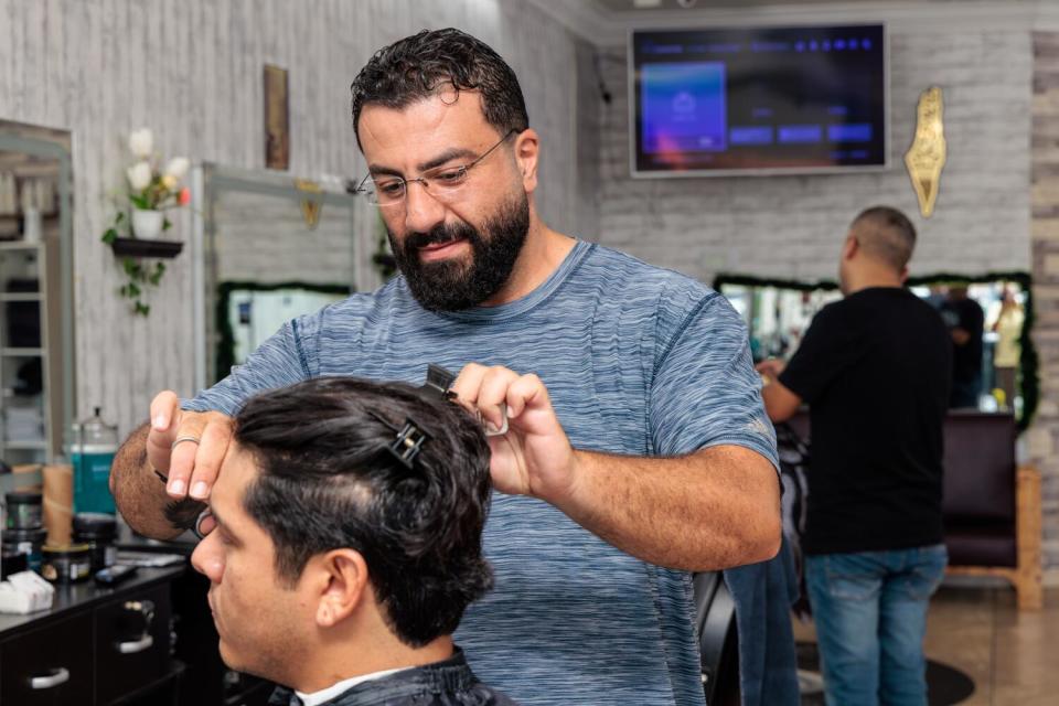 Barber Ahmad Abusadeh cuts a man's hair.