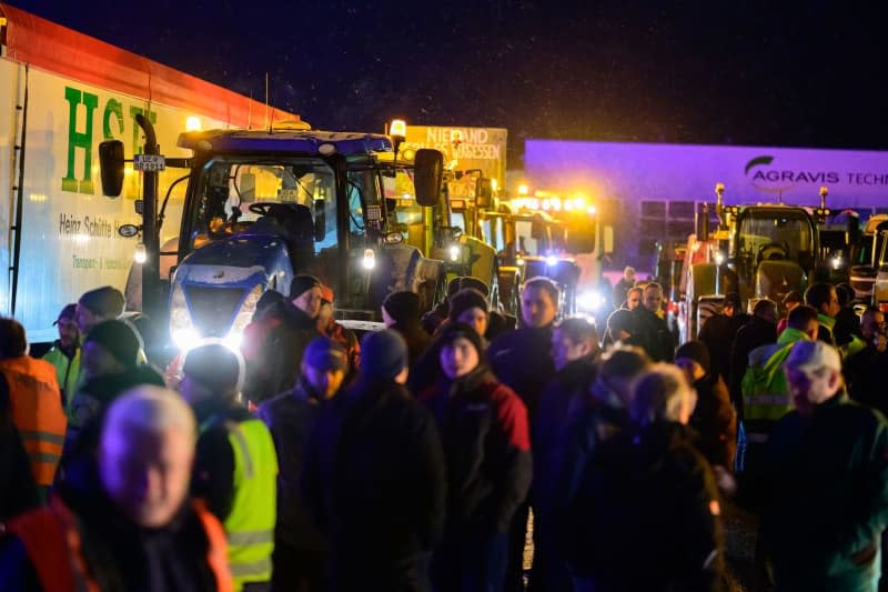 Farmers stand together with truck drivers at a meeting point shortly before they set off on a protest action. In response to the federal government's austerity plans, the farmers' association has called for a week of action with rallies on 8 January. Philipp Schulze/dpa