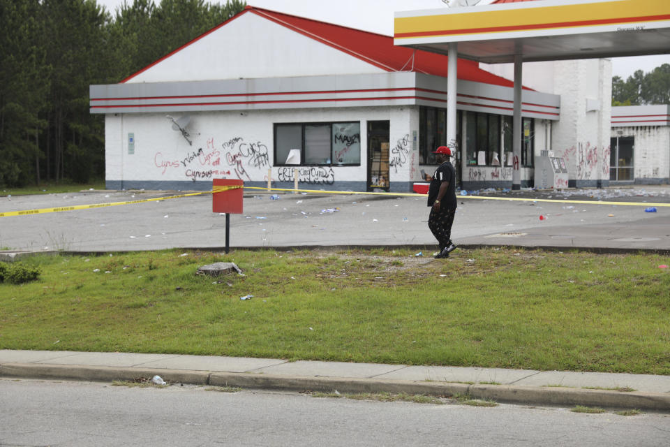 A man walks in front of police tape placed in front of a convenience store, Tuesday, May 30, 2023, in Columbia, S.C. Richland County deputies said the store owner chased a 14-year-old he thought shoplifted, but didn't steal anything and fatally shot the teen in the back. (AP Photo/Jeffrey Collins)