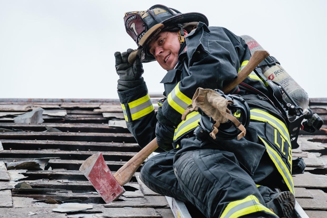 New Philadelphia firefighter Lt. Bobby Smith tips his hat after punching holes through a slate roof during search and rescue training exercises at a donated West High Avenue home in New Philadelphia.