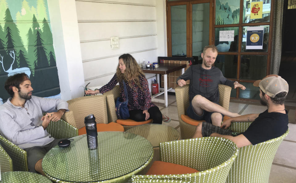 Australian tourist Stewart Dufty, 44, second right, talks with other stranded foreign tourists at a hostel in New Delhi, India, Thursday, April 2, 2020. Dozens of tourists from Britain, Canada and Australia are finding themselves stranded in the Indian capital with their vacations abruptly ended by India’s three-week lockdown and stopping of international flights amid new coronavirus. (AP Photo/Shonal Ganguly)