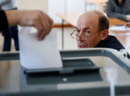 A member of a local electoral commission observes a vote being cast during a presidential election at a polling station in Kozhushna, Moldova October 30, 2016. REUTERS/Gleb Garanich