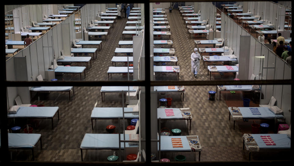 A hospital staff walks past rows of beds at a makeshift COVID-19 care center at an indoor sports stadium in New Delhi, India, Wednesday, July 8, 2020. India has overtaken Russia to become the third worst-affected nation by the coronavirus pandemic. (AP Photo/Altaf Qadri)
