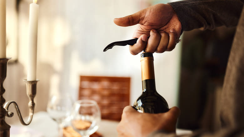 hands opening bottle of wine
