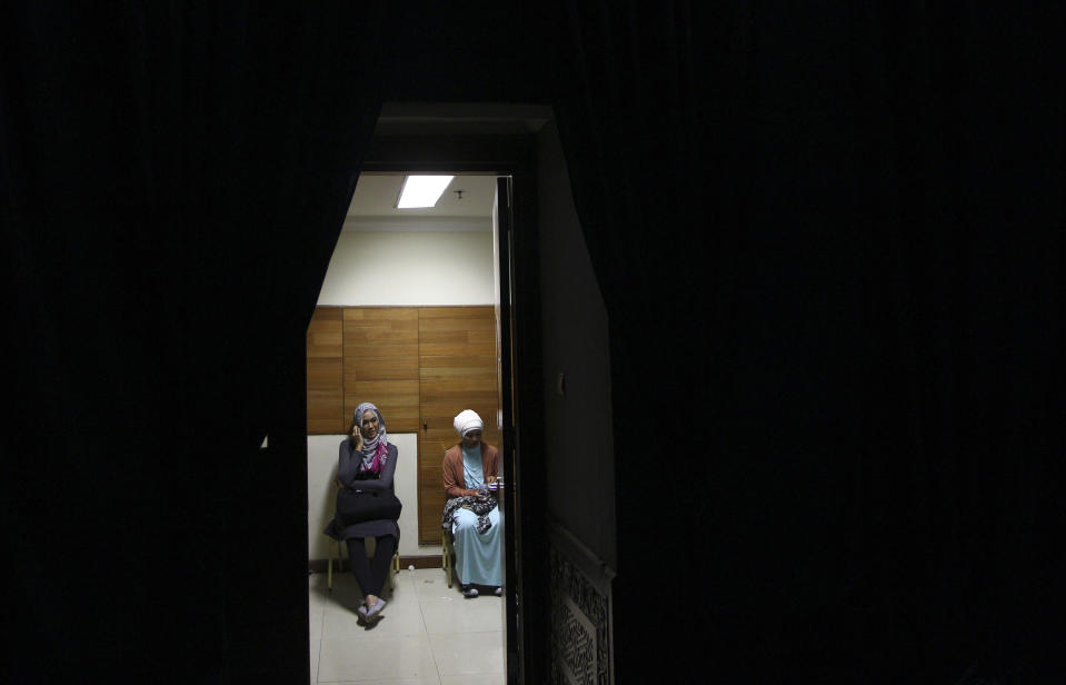 In this Thursday, May 30, 2013 photo, Indonesian Muslim women wait for the start of a fashion show in a backstage changing room during the Islamic Fashion Fair in Jakarta, Indonesia. The event is part of the Indonesian government's effort to turn the most populous Muslim country into the world's Islamic fashion capital by 2020. (AP Photo/Dita Alangkara)