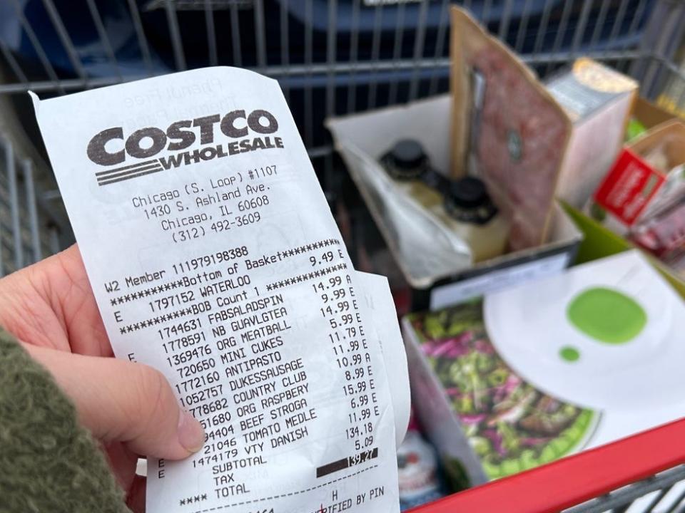 Hand holding receipt in front of Costco car