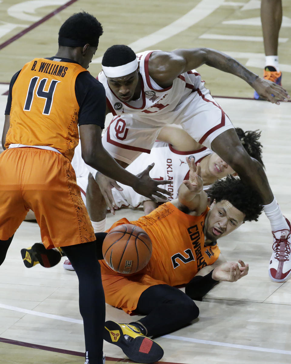 Oklahoma State guard Cade Cunningham (2) passes the ball to guard Bryce Williams (14), away from Oklahoma guard De'Vion Harmon (11) and forward Jalen Hill (1), during the first half of an NCAA college basketball game, Saturday, Feb. 27, 2021, in Norman, Okla. (AP Photo/Garett Fisbeck)