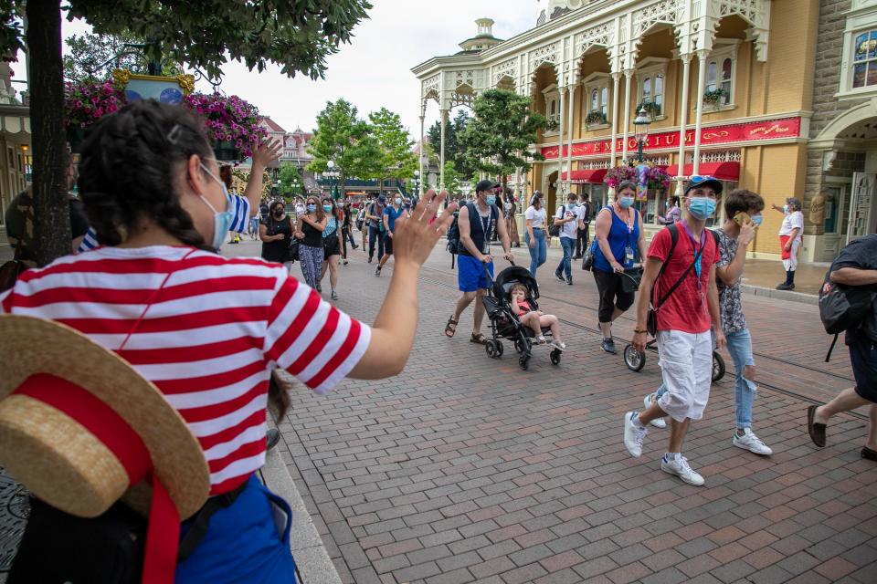 This image shows employees on the left waving at at passing visitors at Disneyland Paris.