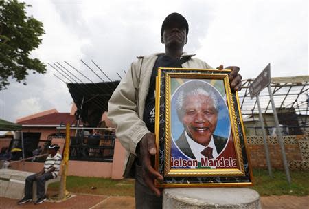 A street vendor sells portraits of Nelson Mandela on Vilakazi Street in Soweto, where the former South African president resided when he lived in the township, December 9, 2013. REUTERS/Yves Herman