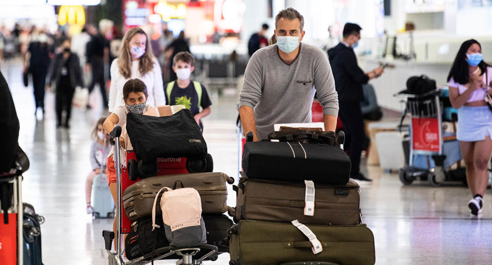 A family walking through an airport with trolleys of luggage.