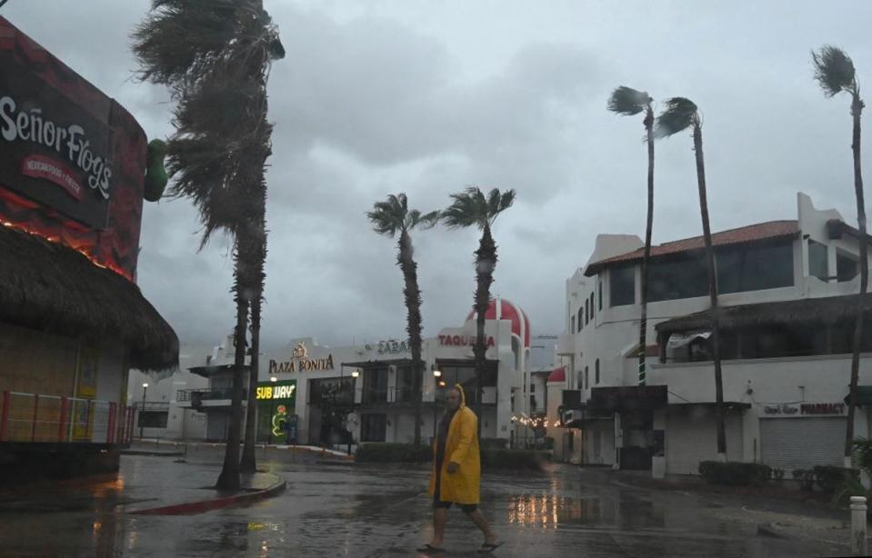 A man walks along a street in Cabo San Lucas, Baja California State, Mexico, as rain and gusts of wind of Hurricane Hilary reach the area (AFP via Getty Images)