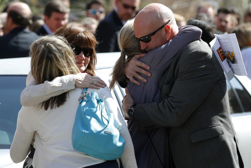 Friends hug after the funeral of Josh Hunter in Calgary