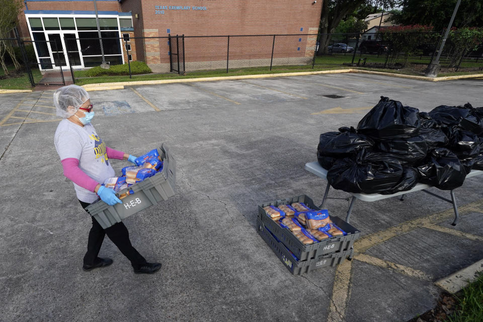 Houston Independent School District Nutrition Services employee Maria Cervatas carries packages of buns to be distributed Monday, April 6, 2020, in Houston. HISD relaunched their food distribution efforts throughout the district Monday, with a streamlined process that will implement increased safety measures. (AP Photo/David J. Phillip)