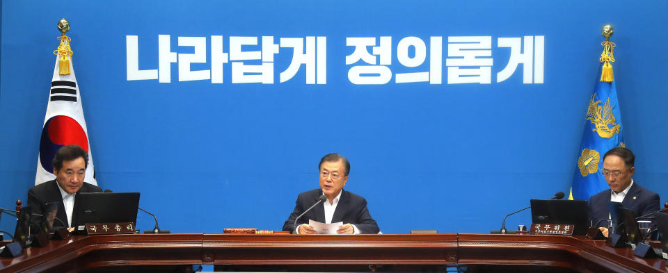 South Korean President Moon Jae-in, center, speaks during an emergency cabinet meeting at the presidential Blue House in Seoul, South Korea, Friday, Aug. 2, 2019. Moon has vowed stern countermeasures against Japan's decision to downgrade its trade status, which he described as a deliberate attempt to contain South Korea's economic growth and a "selfish" act that would damage global supply chains. The sign reads "Righteous." (Bae Jae-man/Yonhap via AP)
