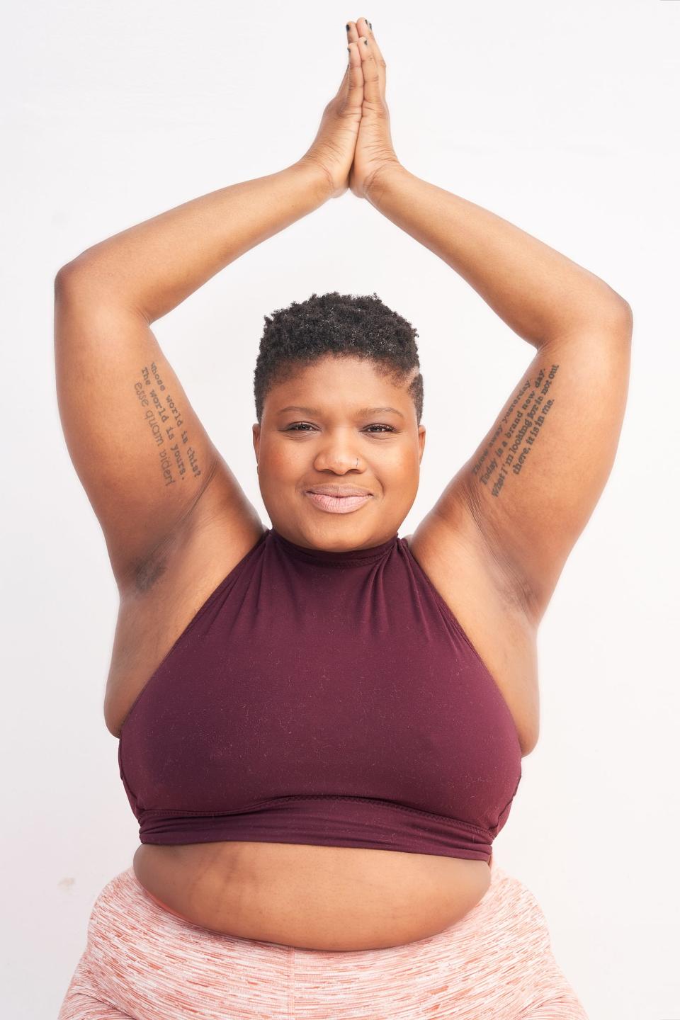 Jessamyn Stanley does a yoga pose while wearing a red, pink, and white two-piece exercise set.