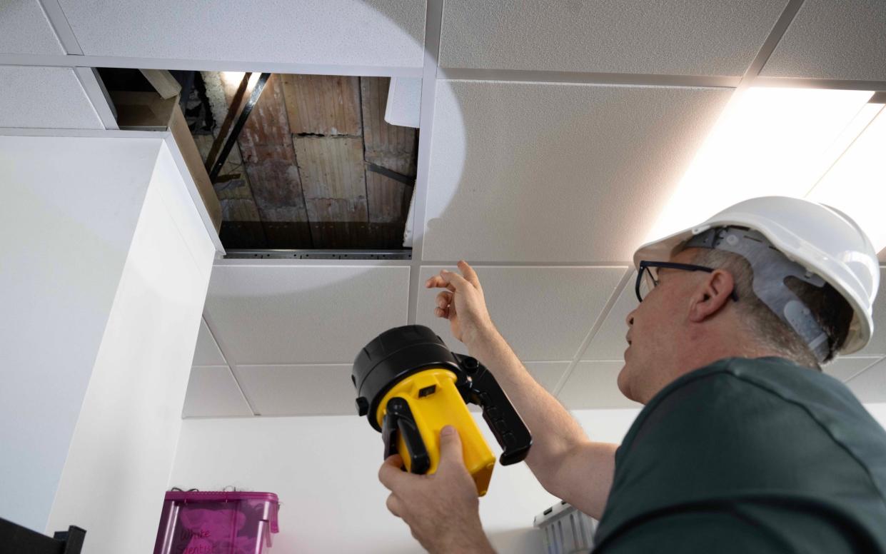 Man inspects concrete in school ceiling