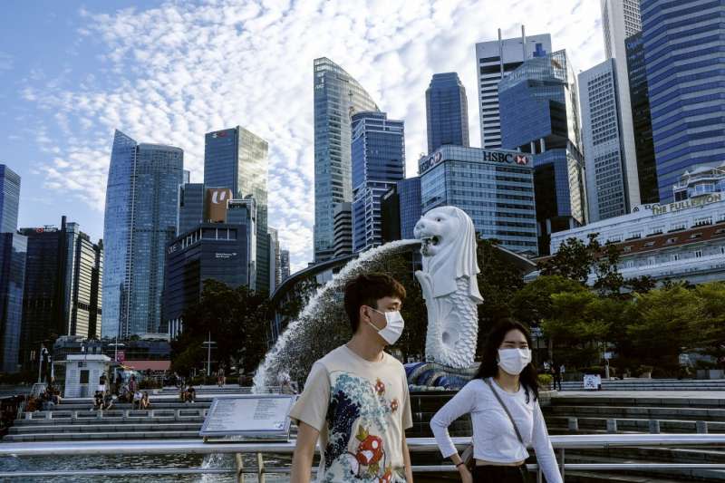 3月14日，戴著口罩的路人行經新加坡魚尾獅公園（美聯社）