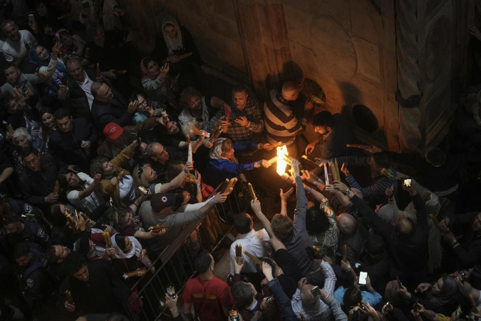 Christian pilgrims light candles during the Holy Fire ceremony, a day before Easter, at the Church of the Holy Sepulcher, where many Christians believe Jesus was crucified, buried and resurrected, in Jerusalem's Old City, Saturday, April 15, 2023. (AP Photo/Mahmoud Illean)