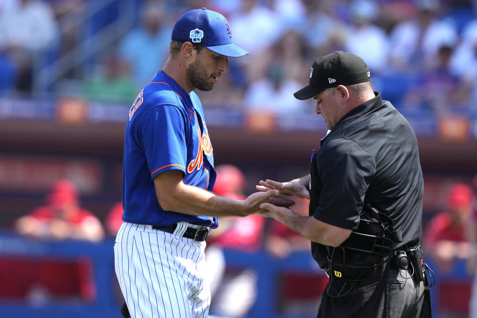 New York Mets starting pitcher Max Scherzer, left, has his hands checked by the home plate umpire after pitching in the first inning of a spring training baseball game, Friday, March 3, 2023, in Port St. Lucie, Fla. (AP Photo/Lynne Sladky)