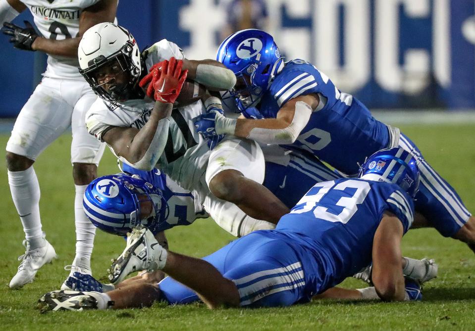 Cincinnati Bearcats running back Corey Kiner (21) gets tackled by Brigham Young Cougars safety Tanner Wall (28), Brigham Young Cougars defensive end Blake Mangelson (93) and Brigham Young Cougars safety Ethan Slade (26) during the second half of a football game at LaVell Edwards Stadium in Provo on Friday, Sept. 29, 2023. BYU won 35-27. | Kristin Murphy, Deseret News