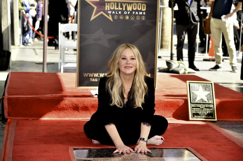 A woman poses with a star on the Hollywood Walk of Fame