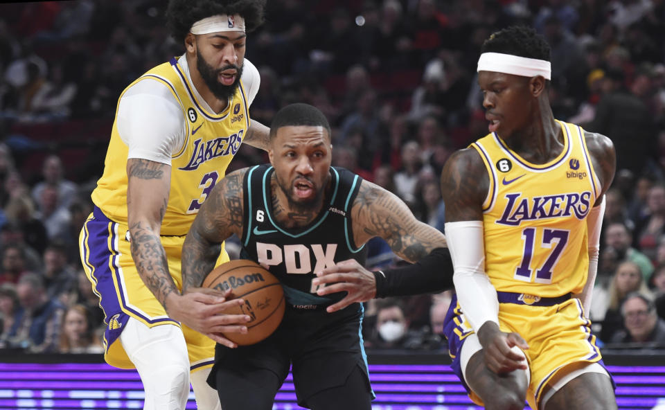 Portland Trail Blazers guard Damian Lillard, center, drives to the basket against Los Angeles Lakers forward Anthony Davis, left, and guard Dennis Schroder, right, during the first half of an NBA basketball game in Portland, Ore., Monday, Feb. 13, 2023. (AP Photo/Steve Dykes)