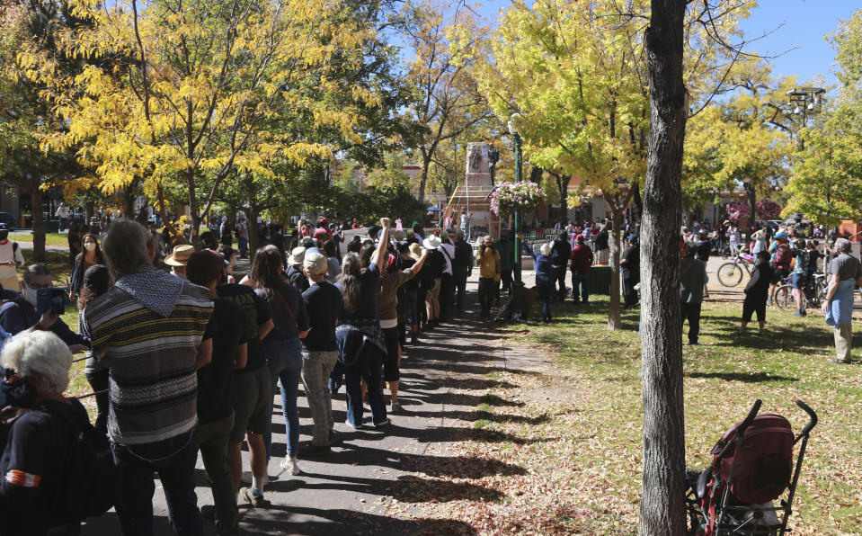 FILE - In this Saturday, Oct. 12, 2020, file photo, a line of demonstrators holds one end of a rope while the other end is secured to a stone obelisk, pulling down segments of a memorial, which commemorates federal soldiers in Santa Fe, New Mexico. The Hispanic cultural association Union Protectiva de Santa Fe sued the city's mayor Wednesday, June 16, 2021, over the destruction of the obelisk by activists the year before and plans to move the memorial permanently. The lawsuit argues that the obelisk, which honors Hispanic soldiers that fought and died for the Union in battles with Confederate soldiers and Indigenous tribes, is a protected historical site. (AP Photo/Cedar Attanasio, File)