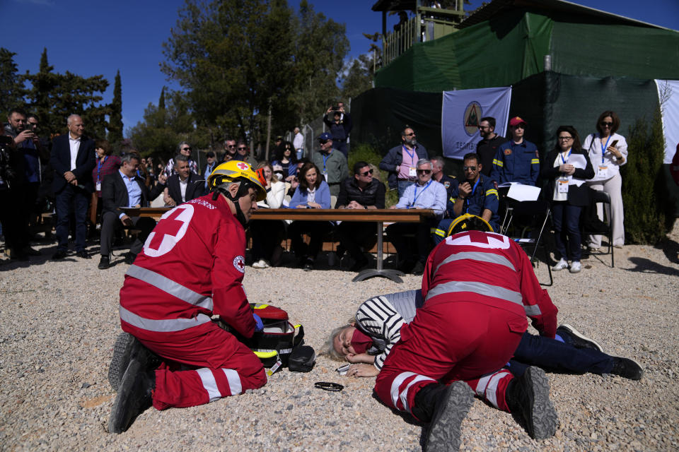 Rescuers assist an actor posing as fire evacuee while officials watch the preparedness drill at Glyka Nera, in northeastern Athens on Thursday, April 4, 2024. Authorities have stepped up exercises ahead of the official start of the fire season on May 1. (AP Photo/Thanassis Stavrakis)