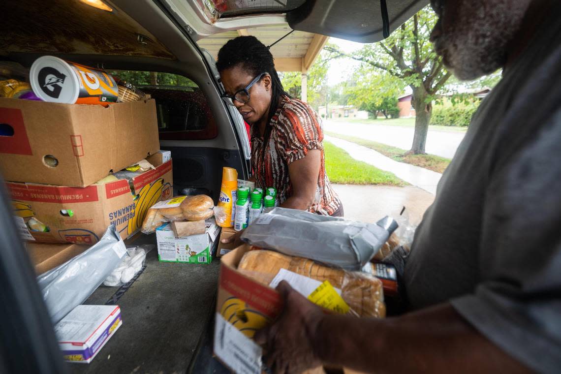 Amani Latimer Burris and Hugh Flake organize Community Food Bank boxes while out delivering food to residents with Opal Lee on Sept. 1 in Fort Worth.