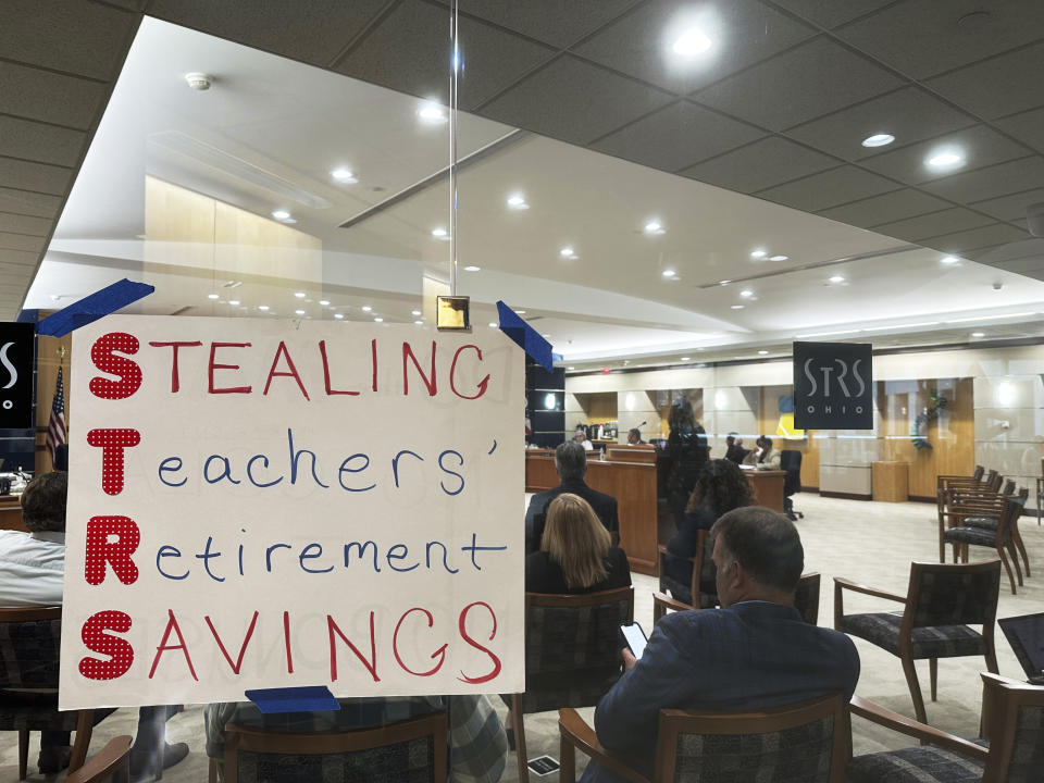 A poster using the initials of the State Teachers Retirement System of Ohio to spell out "Stealing Teachers' Retirement Savings" hangs on the wall during a board meeting at the pension fund's headquarters in Columbus, Ohio, on Wednesday, May 15, 2024. (AP Photo/Julie Carr Smyth)