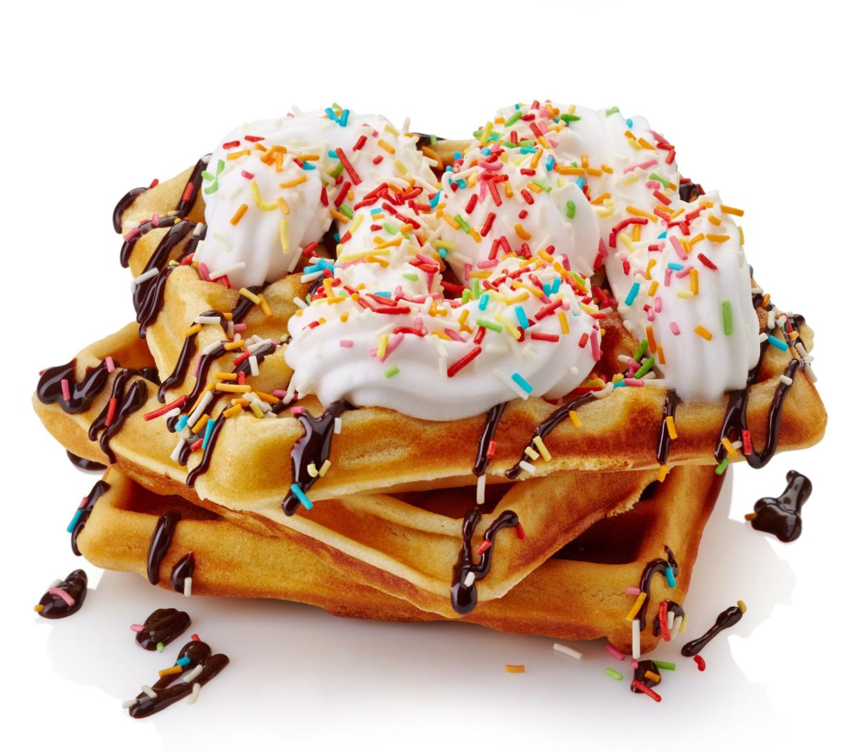 Belgian waffles with whipped cream. chocolate sauce and sprinkles isolated on white background