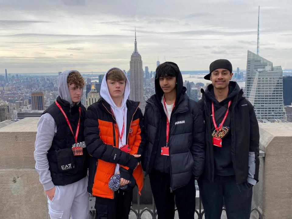 4 students pose on a rooftop in front of a view of the NYC skyline