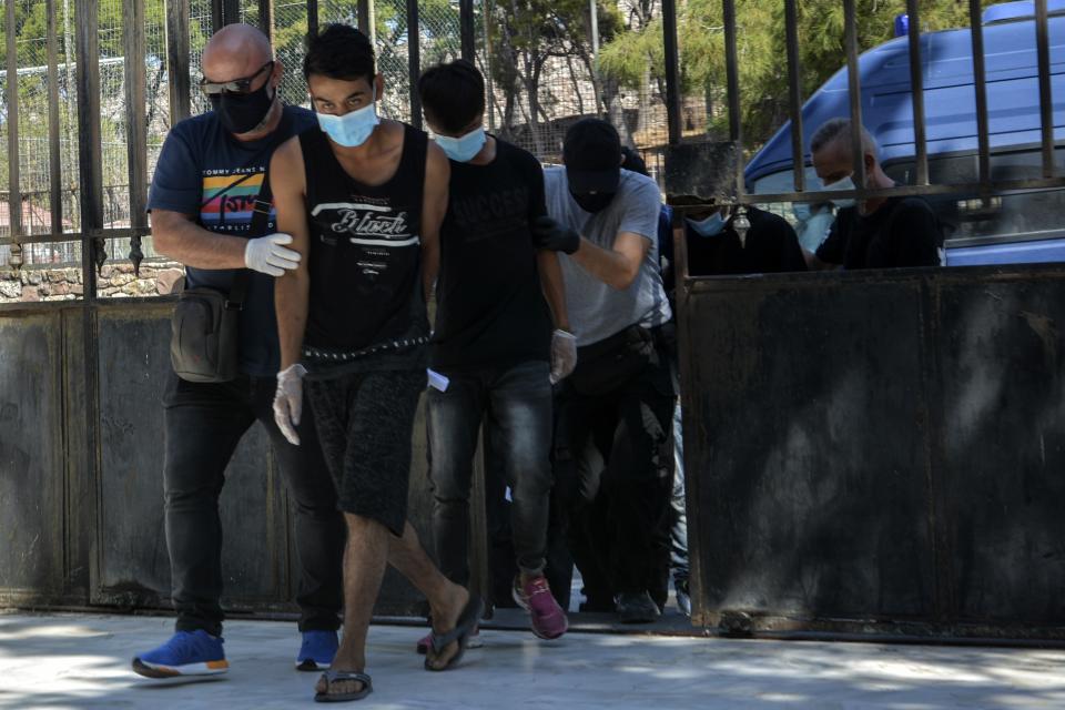 Suspects, all from Afghanistan escorted by plain clothes policemen and wearing face masks, arrive at a court in Mytilene, the capital of the northeastern Aegean island of Lesbos, Greece, Wednesday, Sept. 16, 2020. The government says the fires in Moria refugee camp were set deliberately by the Afghan migrants protesting a coronavirus lockdown, and authorities on Tuesday announced the arrests of six suspect, include two 17-year-olds, in the case. (AP Photo/Panagiotis Balaskas)