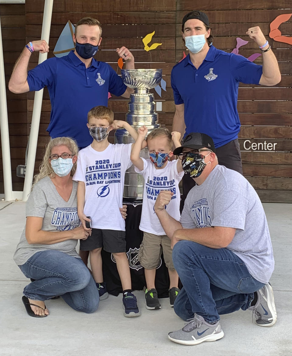 Malissa, front left, and Jesse Black, front right, with 5-year-old son Jase and 7-year-old son Mason, pose with the Stanley Cup and Tampa Bay Lightning players Steven Stamkos, top left, and Ryan McDonagh, top right, at the Children’s Cancer Center in Tampa, Fla., on Oct. 16, 2020. The Lightning took the Stanley Cup to the Children’s Cancer Center as part of their local tour of stops after winning the National Hockey League’s championship trophy Sept. 28 in Edmonton, Alberta. (Kristina Hjertkvist/Tampa Bay Lightning via AP)