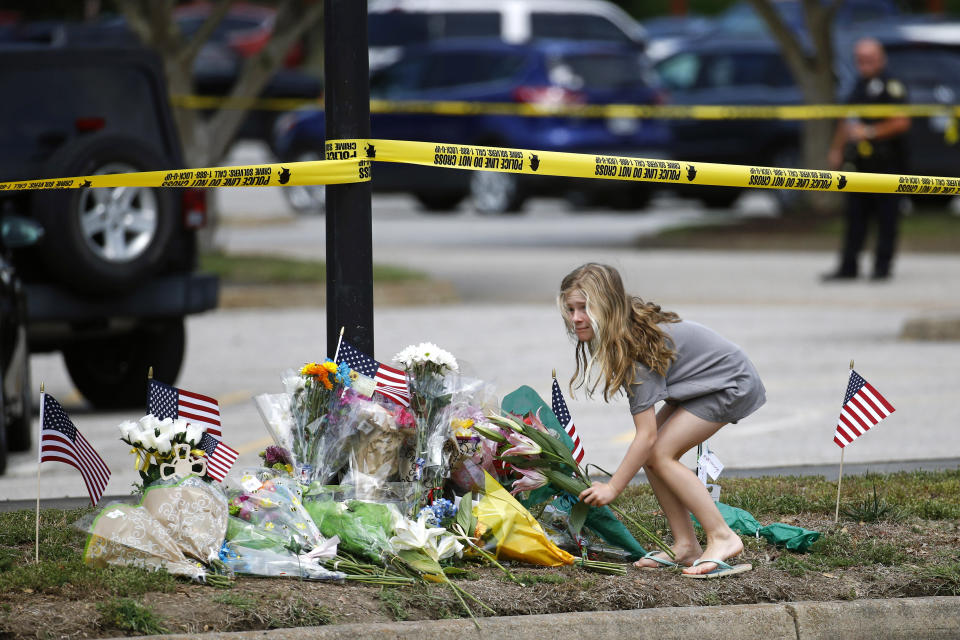 FILE - In this June 1, 2019 file photo, a girl leaves flowers at a makeshift memorial at the edge of a police cordon in front of a municipal building that was the scene of a shooting in Virginia Beach, Va. DeWayne Craddock, a city engineer who fatally shot 12 people in a Virginia Beach municipal building in 2019 “was motivated by perceived workplace grievances” that “he fixated on for years,” according to findings released by the FBI on Wednesday, June 9, 2021. (AP Photo/Patrick Semansky, File)