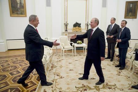 Russian President Vladimir Putin (R) approaches to shake hands with Israeli Prime Minister Benjamin Netanyahu during a meeting in Moscow, Russia, March 9, 2017. REUTERS/Pavel Golovkin/Pool