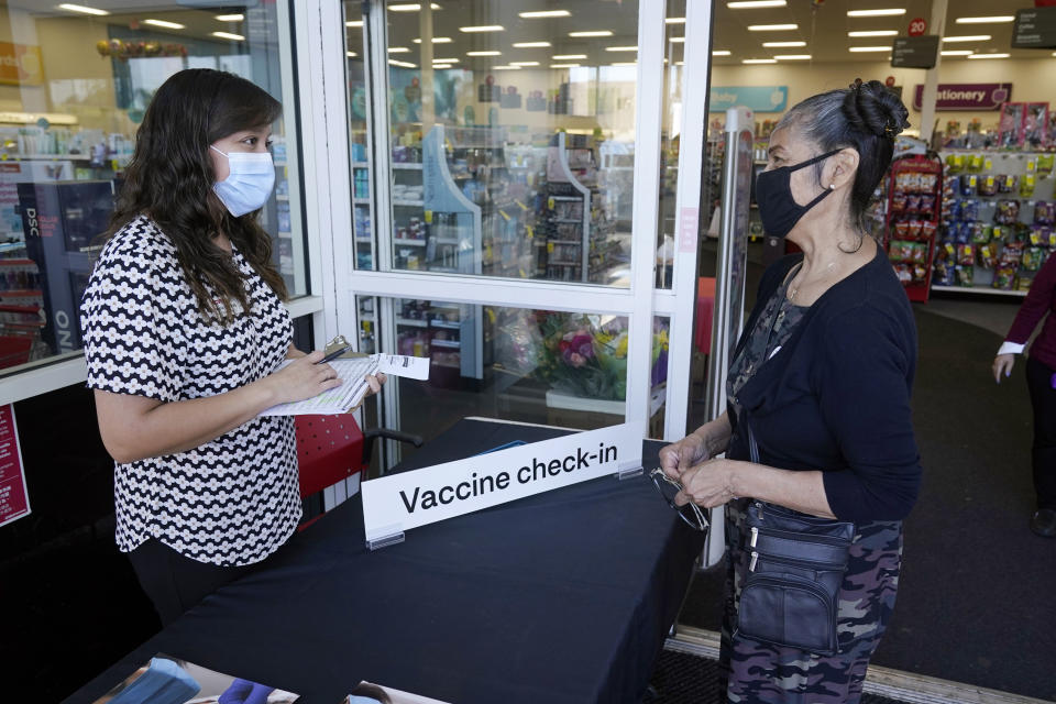 FILE - Belinda Perez, left, checks in with store manager Maria Gallardo at a COVID-19 vaccination site inside a CVS Pharmacy branch on March 1, 2021, in Los Angeles. A rush of vaccine-seeking customers and staff shortages are squeezing drugstores around the country. That has led to frazzled workers and even temporary pharmacy closures. (AP Photo/Marcio Jose Sanchez, File)