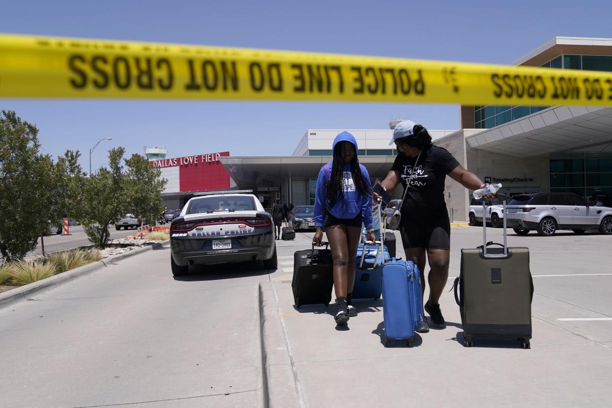 Travelers walk to a parking area outside of Dallas Love Field in Dallas, Monday, July 25, 2022. 