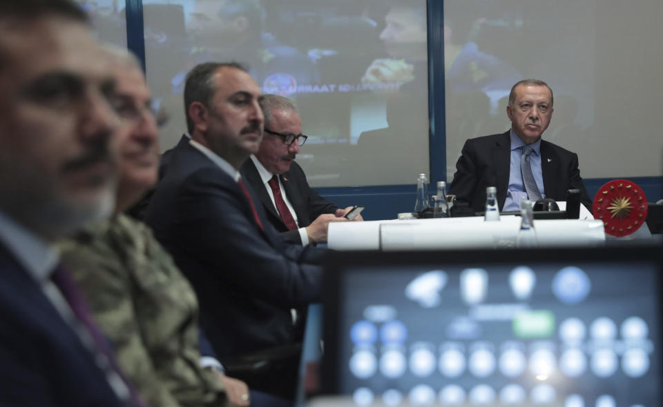 Turkey's President Recep Tayyip Erdogan, right, with military and Intelligence chiefs, ministers and his ruling party members in an operations room at the presidential palace, in Ankara, Turkey, Wednesday, Oct. 9, 2019. Turkey's Defense Ministry said Wednesday that Turkish ground forces have moved against Kurdish fighters across the border in northeastern Syria, hours after Turkish jet and artillery pounded areas in Syria's northern border. (Turkish Presidency Press Service via AP, Pool)