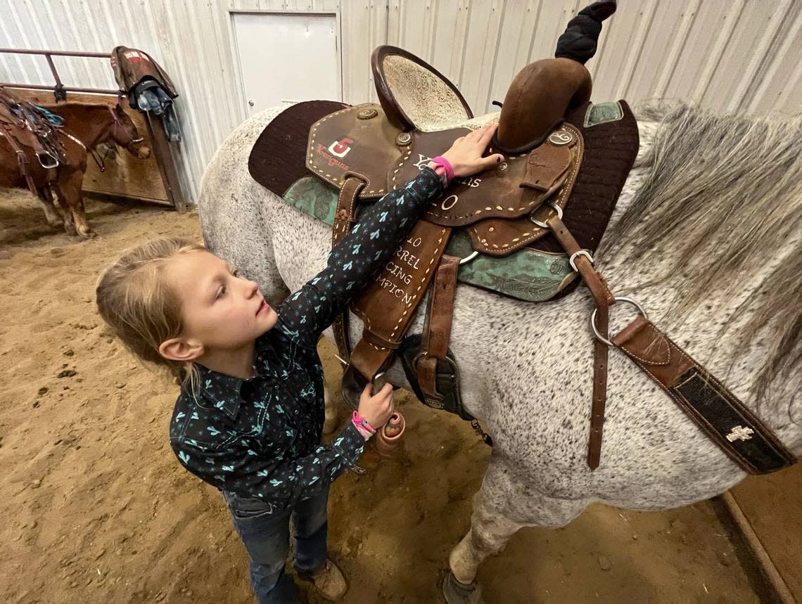 Braylin Barratt, age nine, checks some of the tack strapped to her horse Jesse.