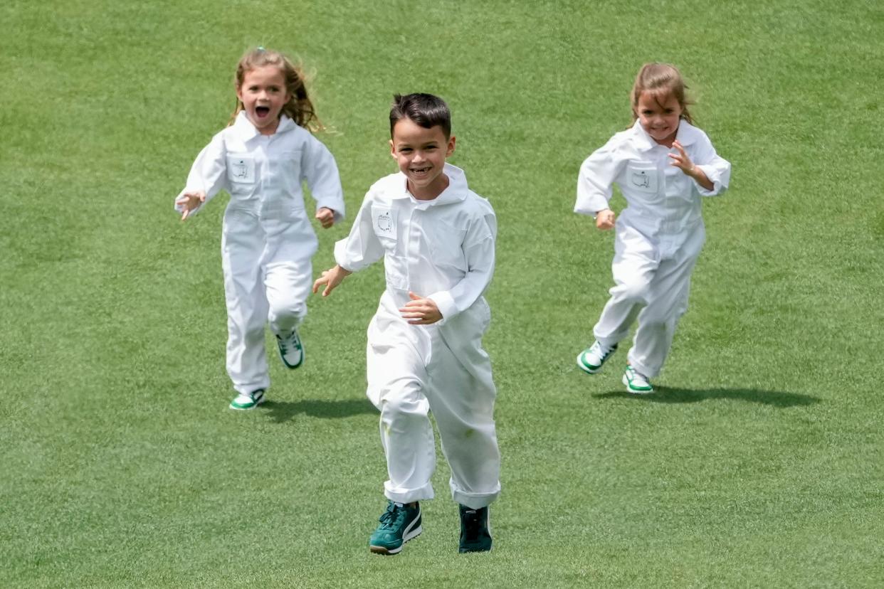 Apr 10, 2024; Augusta, Georgia, USA; Jax Woodland is chased by his sisters, Maddox and Lennox, down the no. 4 fairway during the Par 3 Contest at Augusta National Golf Club. Mandatory Credit: Michael Madrid-USA TODAY Network