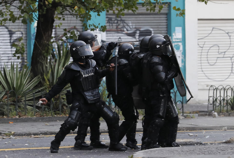 A police prepares to throw a stone at protesters in Quito, Ecuador, Friday, Oct. 4, 2019, during a nationwide transport strike that shut down taxi, bus and other services in response to a sudden rise in fuel prices. Ecuador's President Lenín Moreno, who earlier declared a state of emergency over the strike, vowed Friday that he wouldn't back down on the decision to end costly fuel subsidies, which doubled the price of diesel overnight and sharply raised gasoline prices. (AP Photo/Dolores Ochoa)