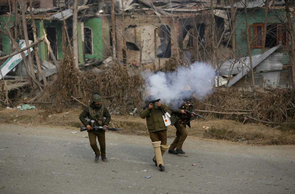 An Indian policeman fires a tear gas shell towards Kashmiri protesters near the site of a gun-battle in Mujagund area some 25 Kilometers (16 miles) from Srinagar, Indian controlled Kashmir, Sunday, Dec. 9, 2018. Indian troops killed three suspected rebels in the outskirts of disputed Kashmir's main city ending nearly 18-hour-long gunbattle, officials said Sunday. (AP Photo/Mukhtar Khan)