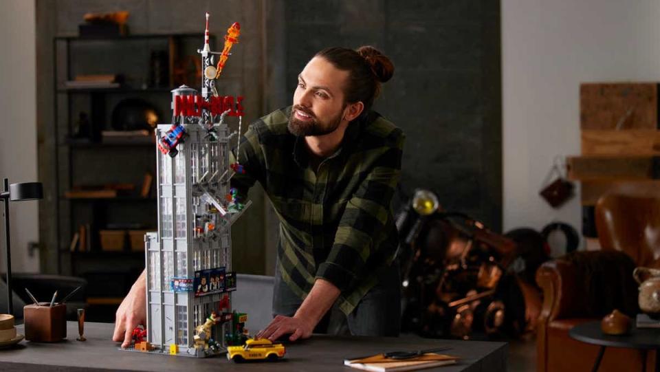 A person looks over the completed LEGO Daily Bugle set on a table