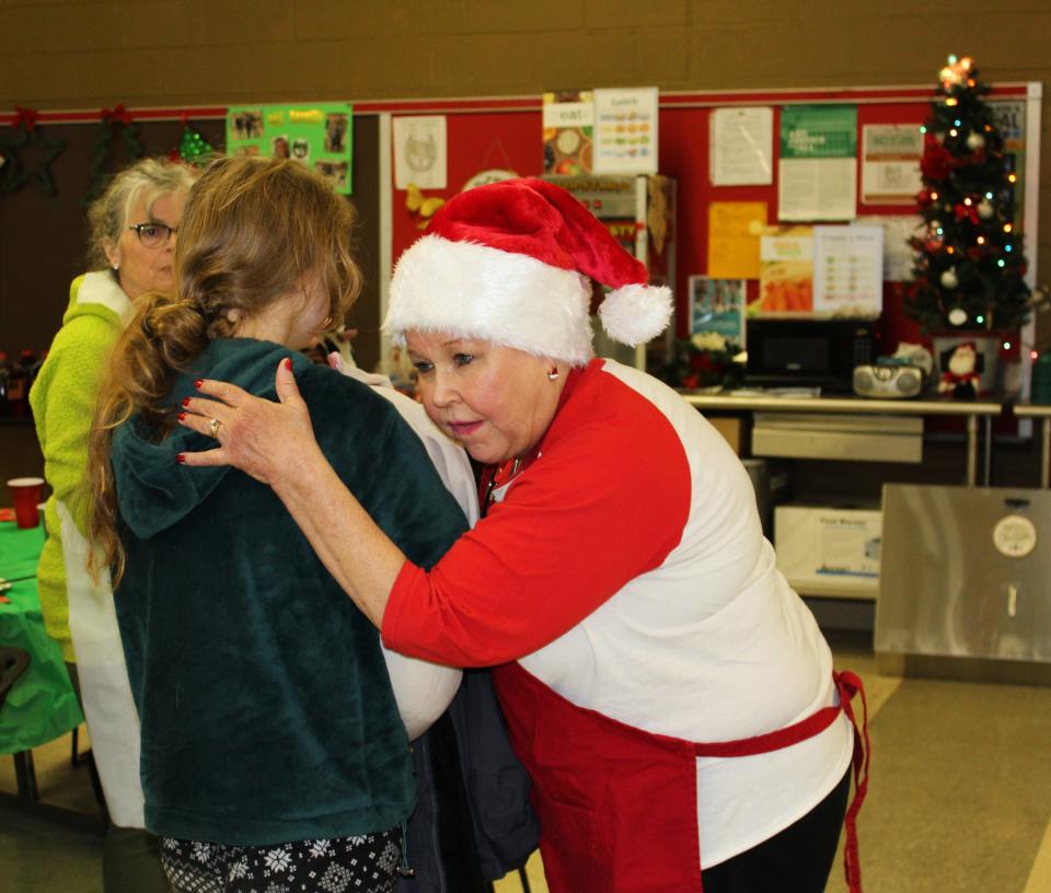 Oakland Academy's Gail McCormick hugs a student during the Thursday, Dec. 21, 2023, holiday party. Gail, who is a cancer patient, works the front desk and was the inspiration for students' $300 donation this year to the Community Cancer Network.