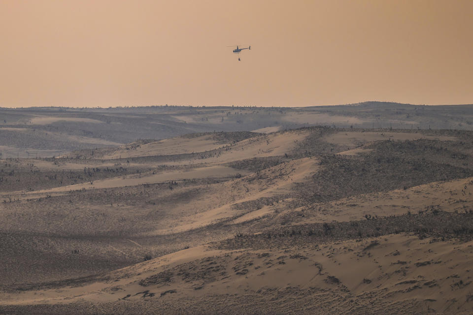 A helicopter returns from dumping water on hotspots from the Smokehouse Creek Fire, Wednesday, Feb. 28, 2024, in Canadian, Texas. (AP Photo/David Erickson)