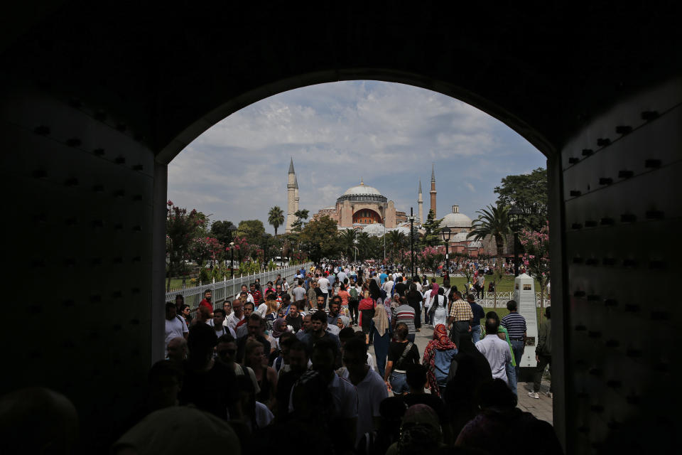 FILE - In this Friday, Aug. 17, 2018 file photo, visitors walk towards the Byzantine-era Hagia Sophia, one of Istanbul's main tourist attractions, in the historic Sultanahmet district of Istanbul. The 6th-century building is now at the center of a heated debate between conservative groups who want it to be reconverted into a mosque and those who believe the World Heritage site should remain a museum. (AP Photo/Lefteris Pitarakis, File)