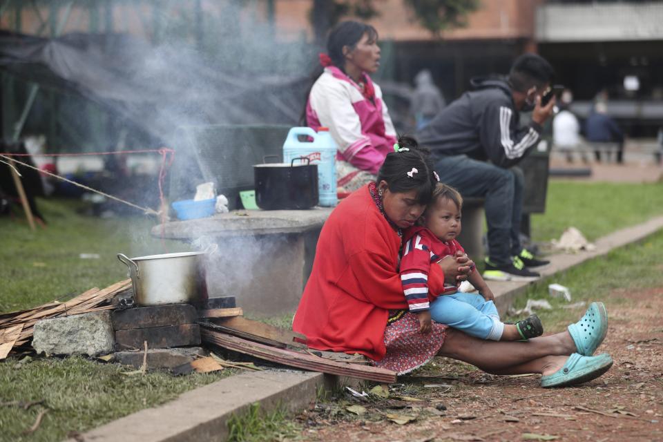 Miembros de la tribu Embera-Katio están sentados en un parque donde establecieron un refugio tras ser desalojados de sus horas por no pagar la renta debido a la pandemia del nuevo coronavirus en Bogotá, Colombia, el viernes 19 de junio de 2020. (AP Foto/Fernando Vergara)