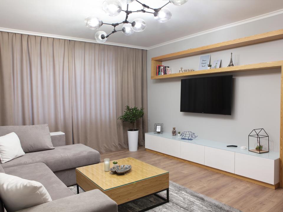 Overhead light fixture in living room with light-brown wooden details and gray furniture